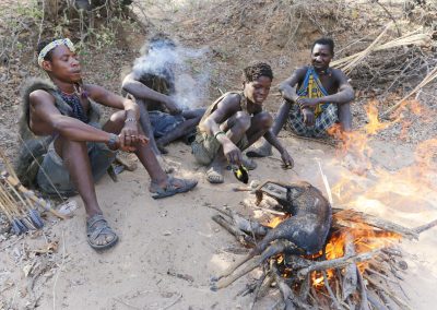 Young Hadzabe men roasting an antelope for food